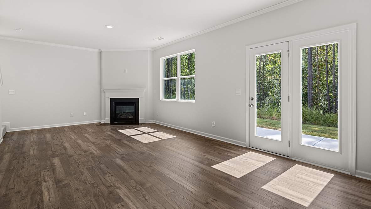 Open concept living room with a fireplace, double window and a glass back door in the dining area.