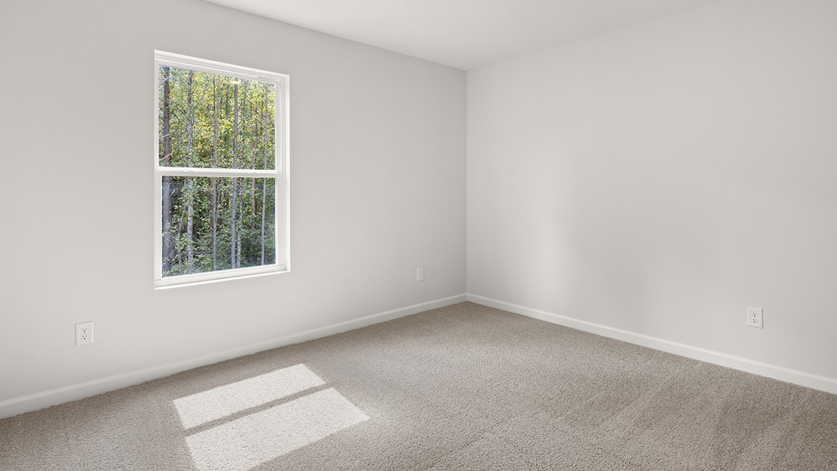 Loft area with a single window and neutral carpet .