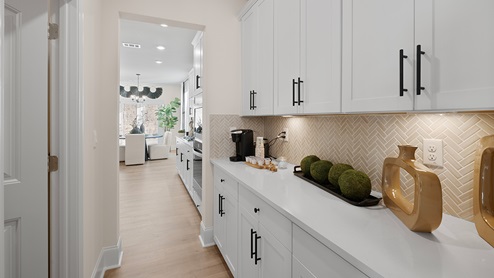 Butner Estates community model home butlers pantry off of the kitchen and dining room with white cabinets and hardware for a bar area