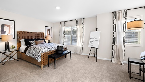 Bedroom with carpeted floors and two windows for natural lighting.