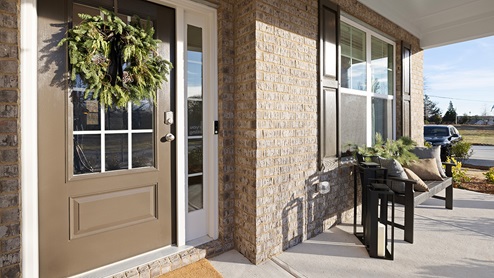 Front exterior of model home with brick siding and covered porch.