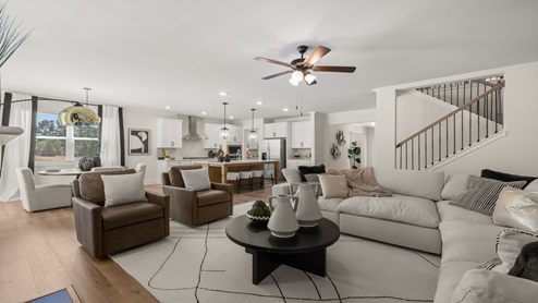 Butner Estates community model home open concept living room with hardwood like flooring and a center ceiling fan