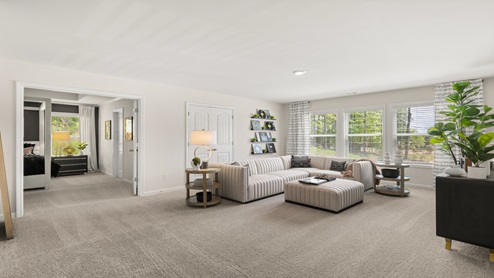Butner Estates community model home second floor loft area with light carpet and multiple windows for natural light used as a living space