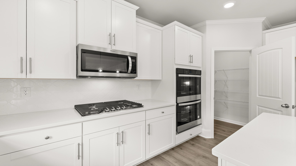 Kitchen and family room blend together with soft color palette, pendant lighting, and access to dining nook and backyard views in New Home For Sale.