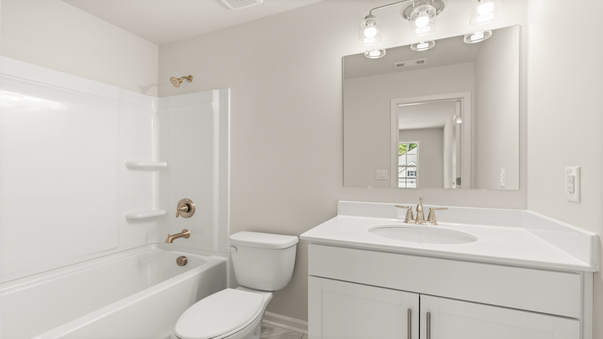 Spacious en suite bathroom by D.R. Horton featuring soft neutral tones, hard surface finishes, and dual sink design