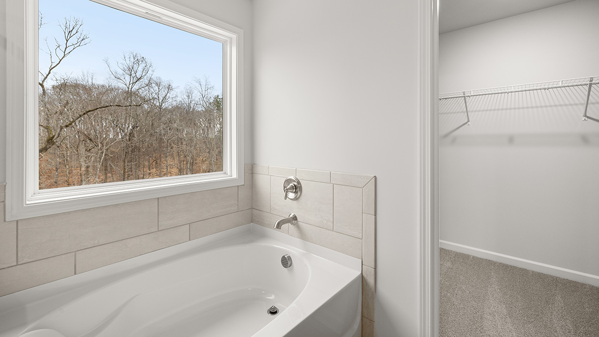 Interior primary bathroom with bath tub and walk-in closet