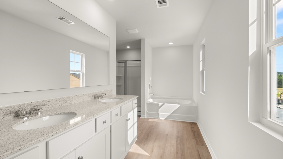 Interior primary bathroom with double sink, shower and bath tub