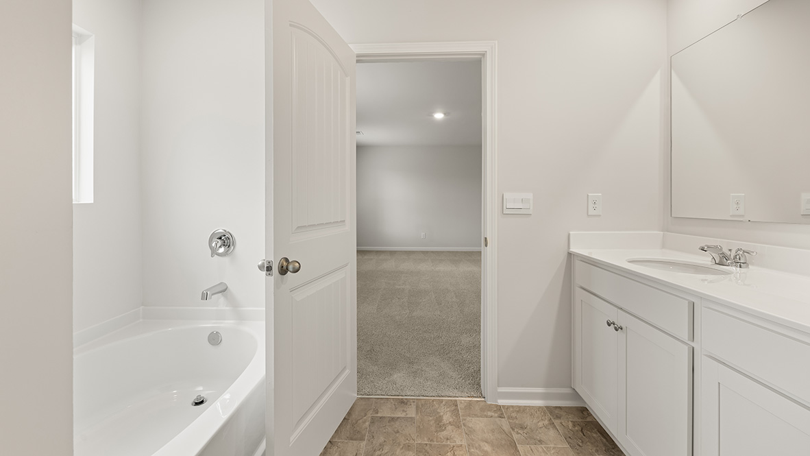 Interior primary bathroom with bath tub, double sink and closet