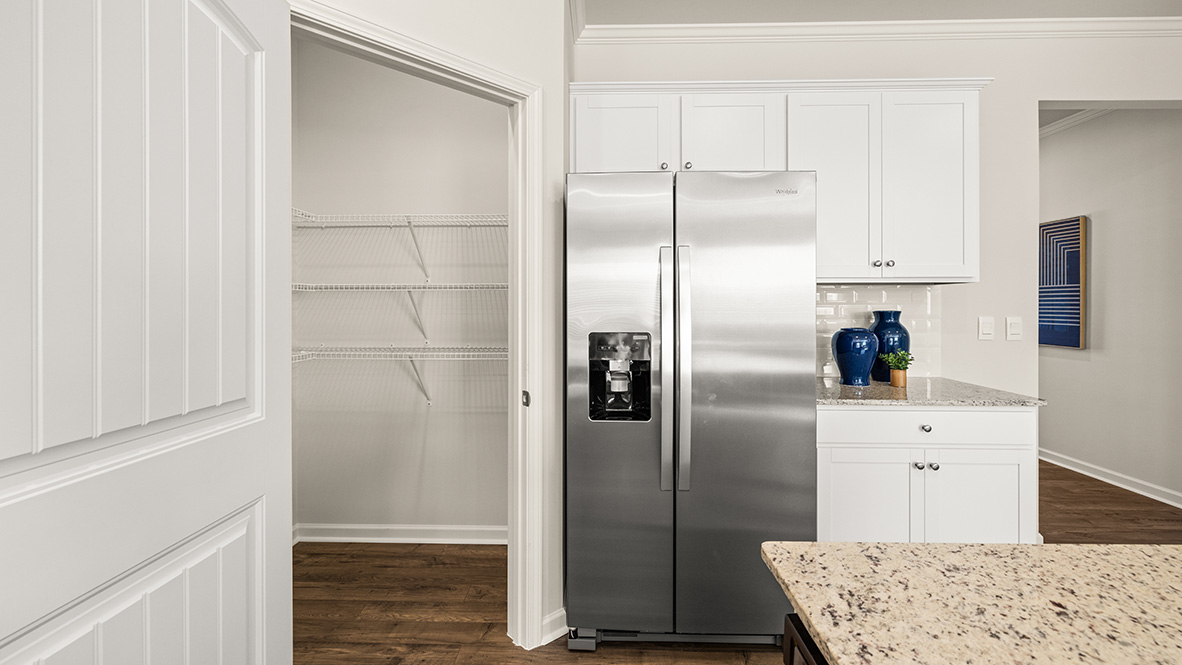Interior kitchen with center island and white cabinets and pantry