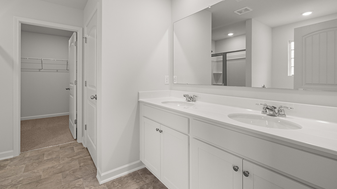 Interior primary bathroom with double sink and walk-in closet