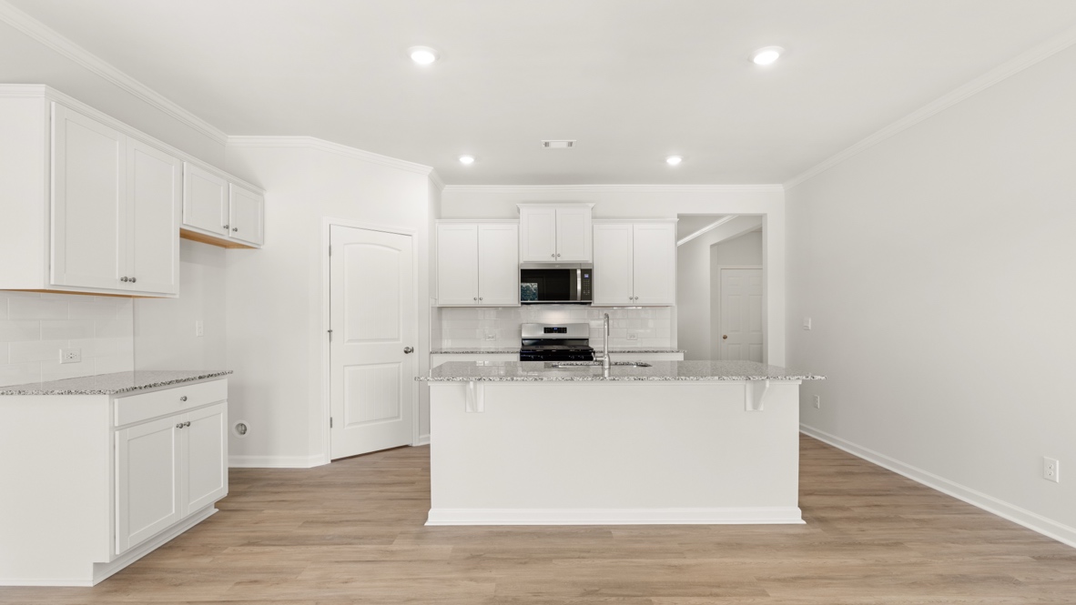 Kitchen with island, stove, microwave, and white cabinets.
