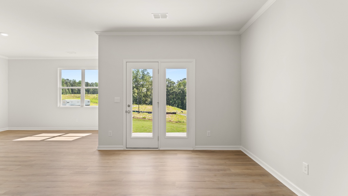 Living space with large windows, wood flooring, and view of back door.