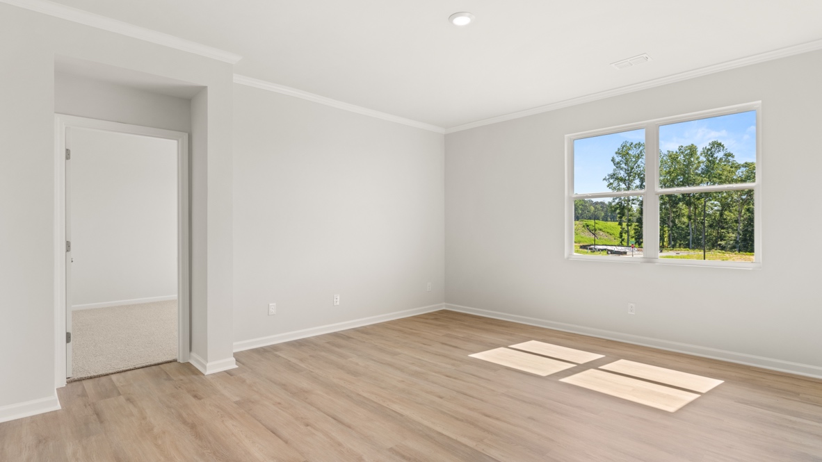 Open living area with wood flooring and view toward kitchen and hallway.
