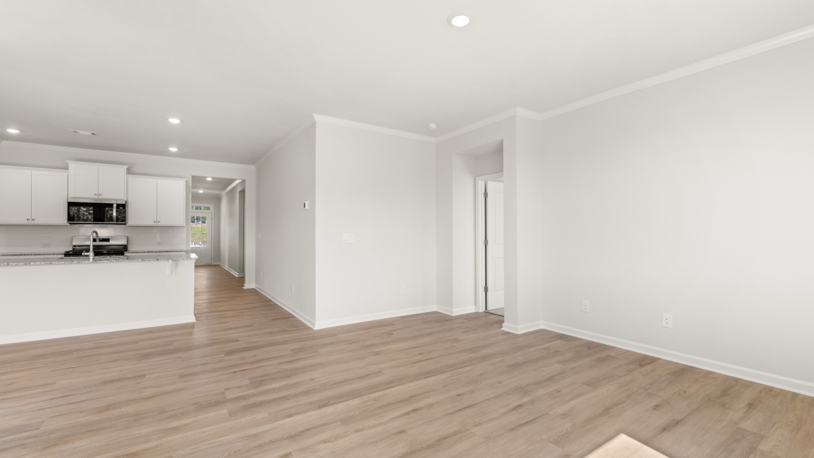 Open living area with wood flooring and view toward kitchen.