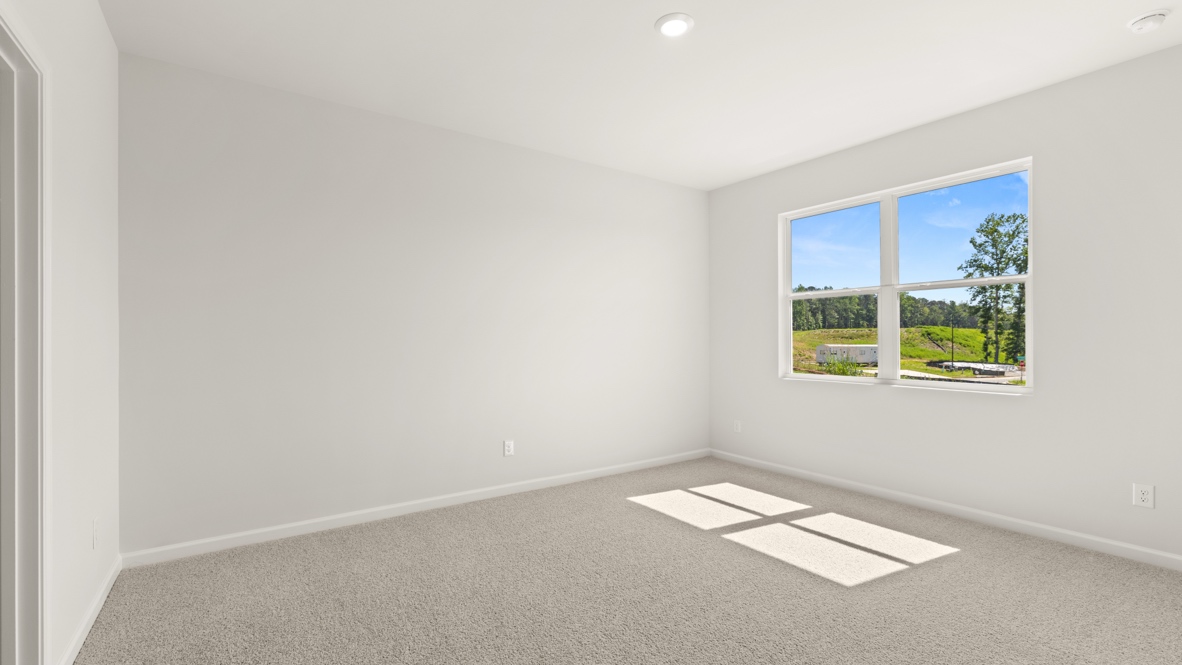 Bedroom with carpet flooring and doorway to bathroom.
