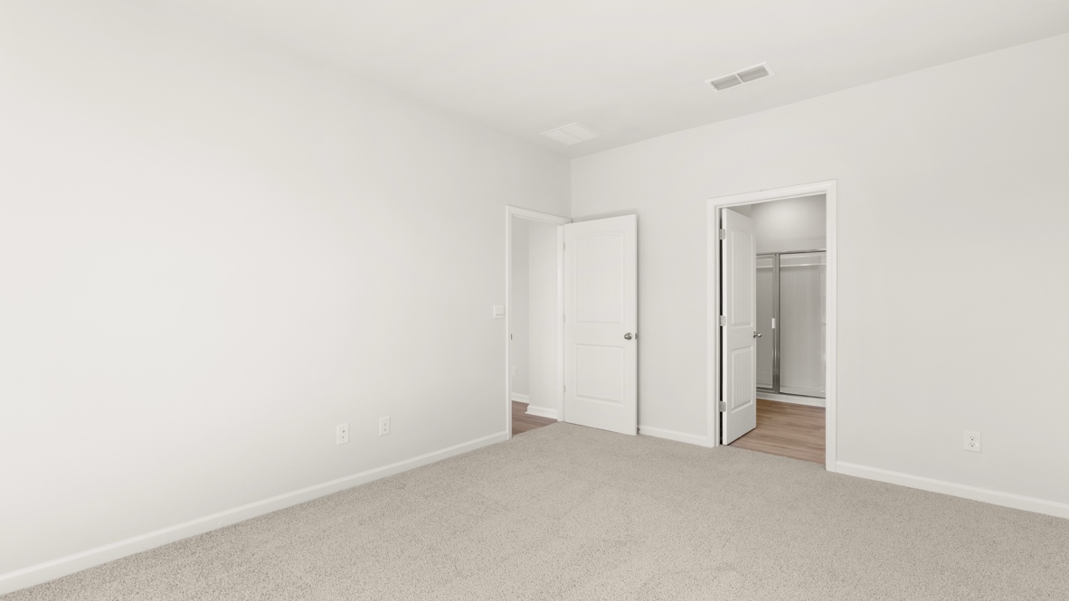 Bedroom with carpet flooring and doorway to bathroom.