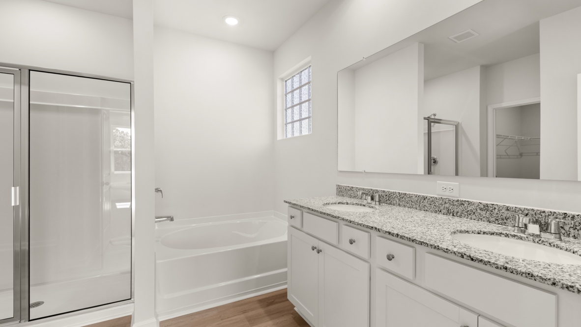 Bathroom with double sink vanity, large mirror, and doorway to bedroom.