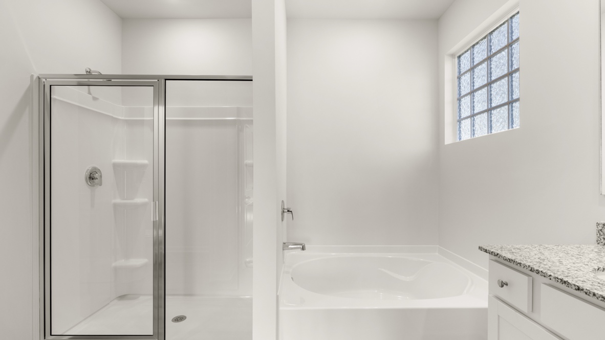Bathroom with glass shower and bathtub with window.