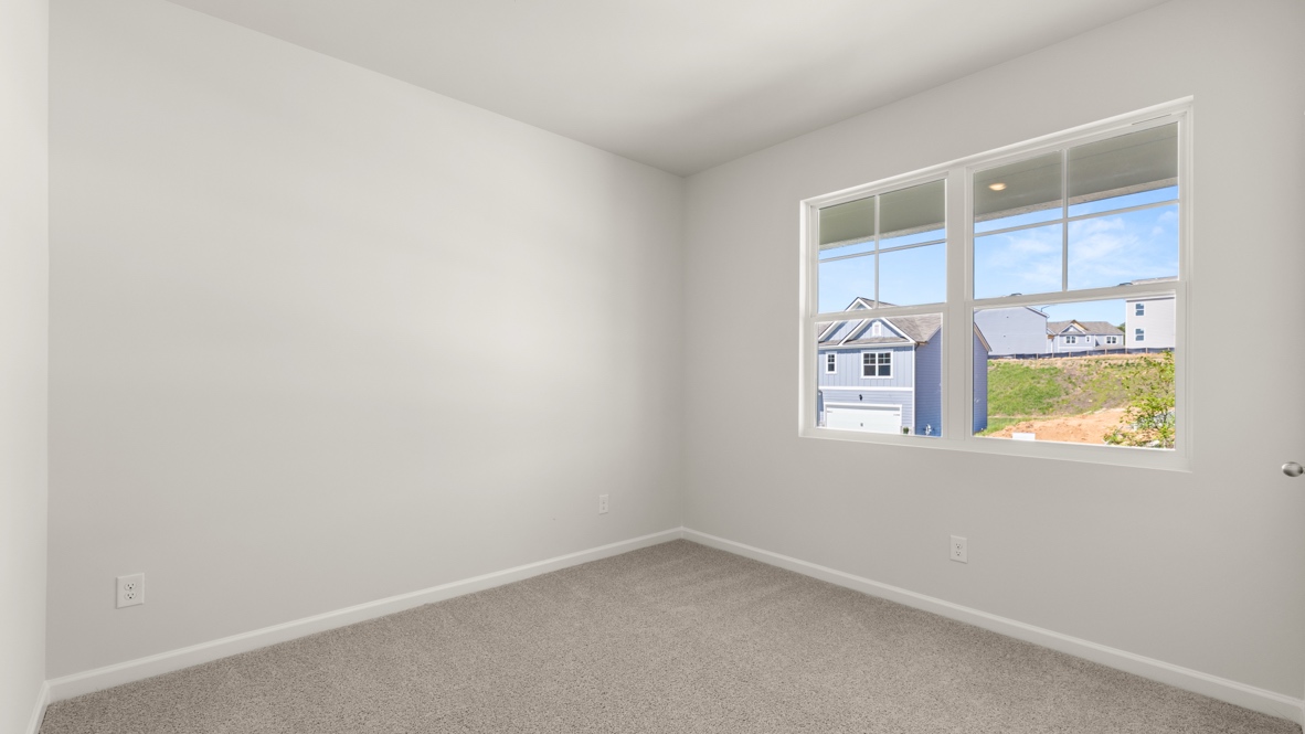 Empty bedroom with carpet flooring and large window with neighborhood view.