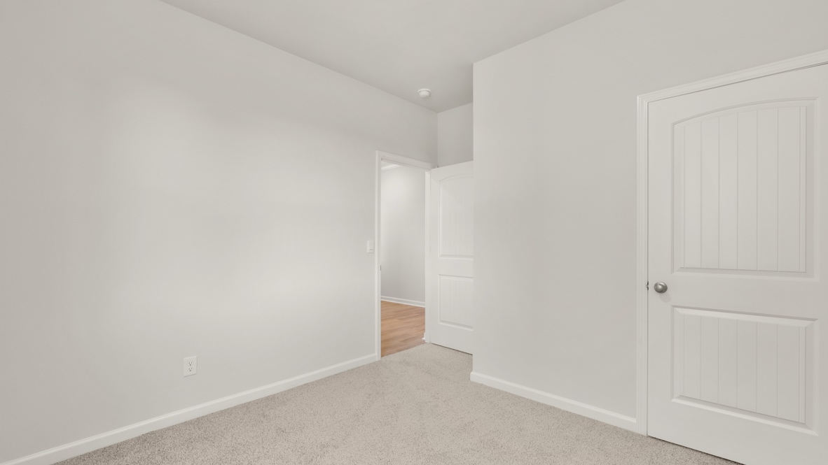 Bedroom with carpet flooring, white walls, and open doorway to hallway.