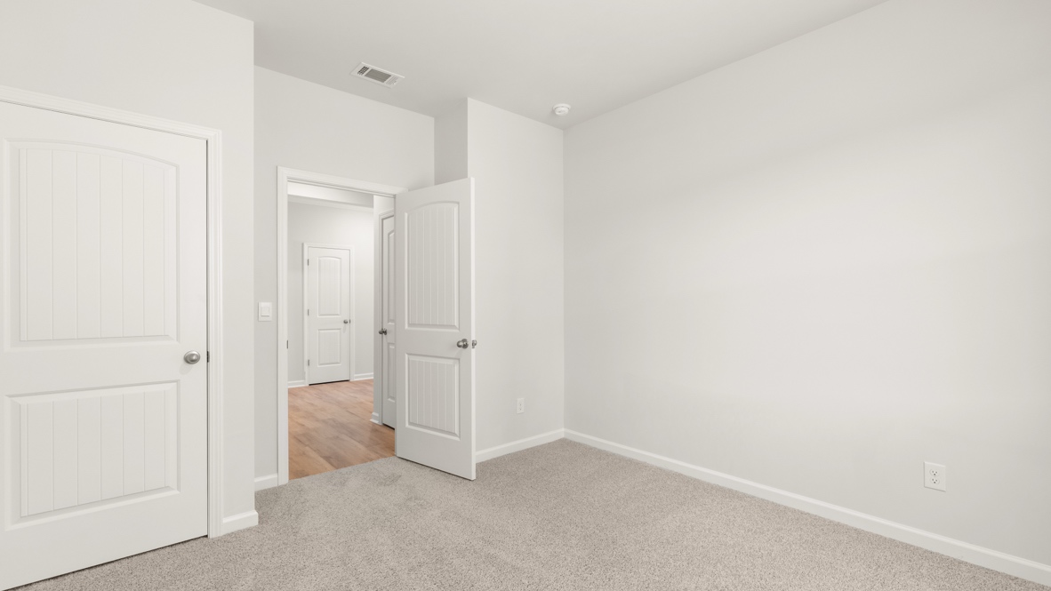 Bedroom with carpet flooring, multiple doors, and open view to hallway