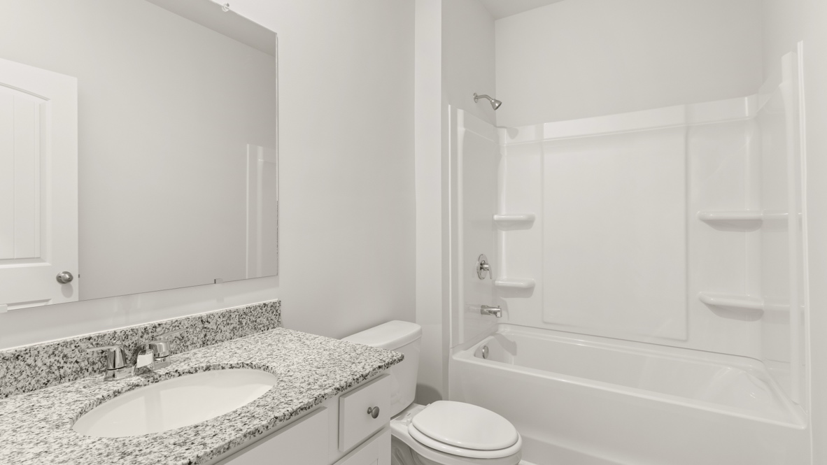 Bathroom with granite countertop, sink, mirror, toilet, and tub shower combo.