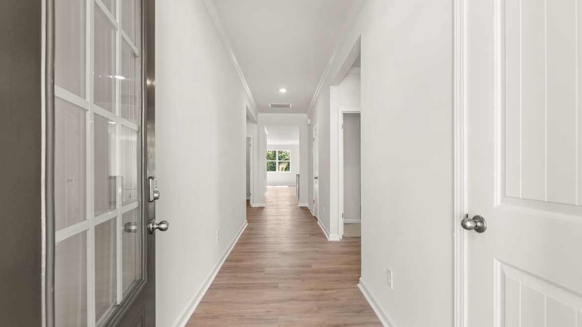 Entry hallway with wood flooring, white walls, and doorways leading to interior rooms.