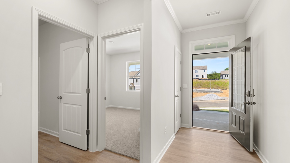 Entry view with open front door, hallway, and bedroom doorway with window.