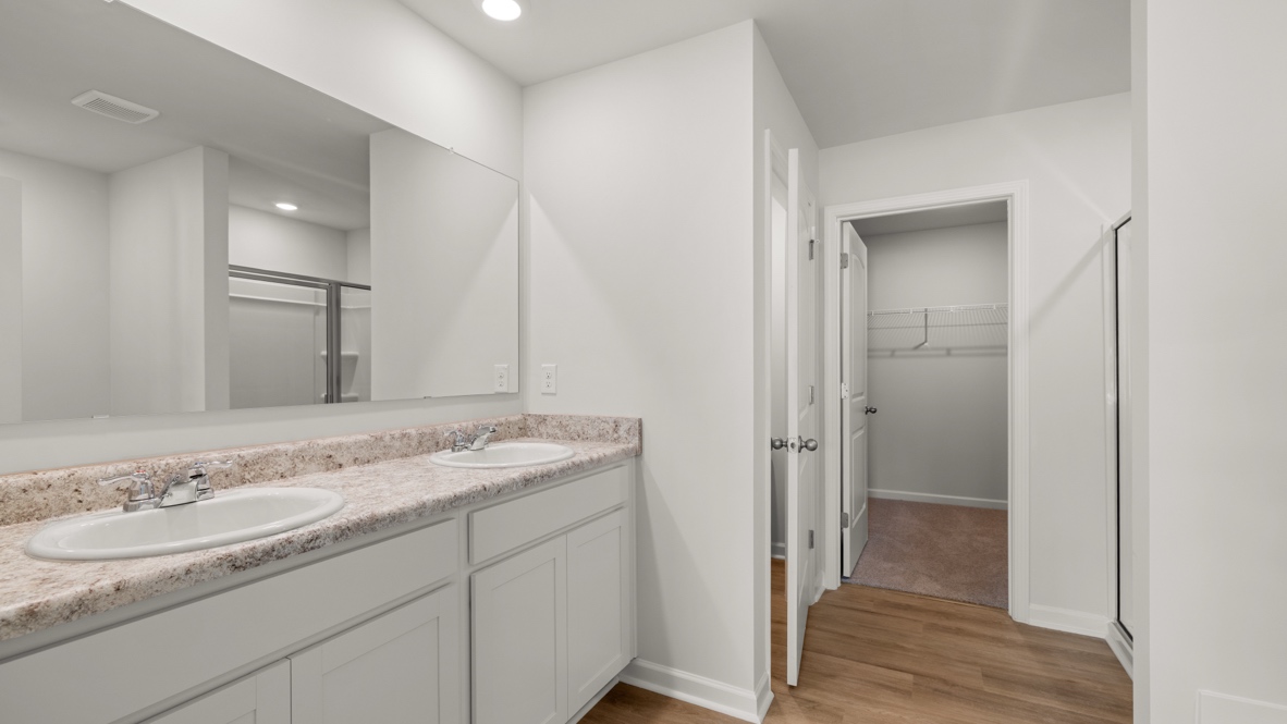 Interior primary bathroom with double sink and walk-in closet