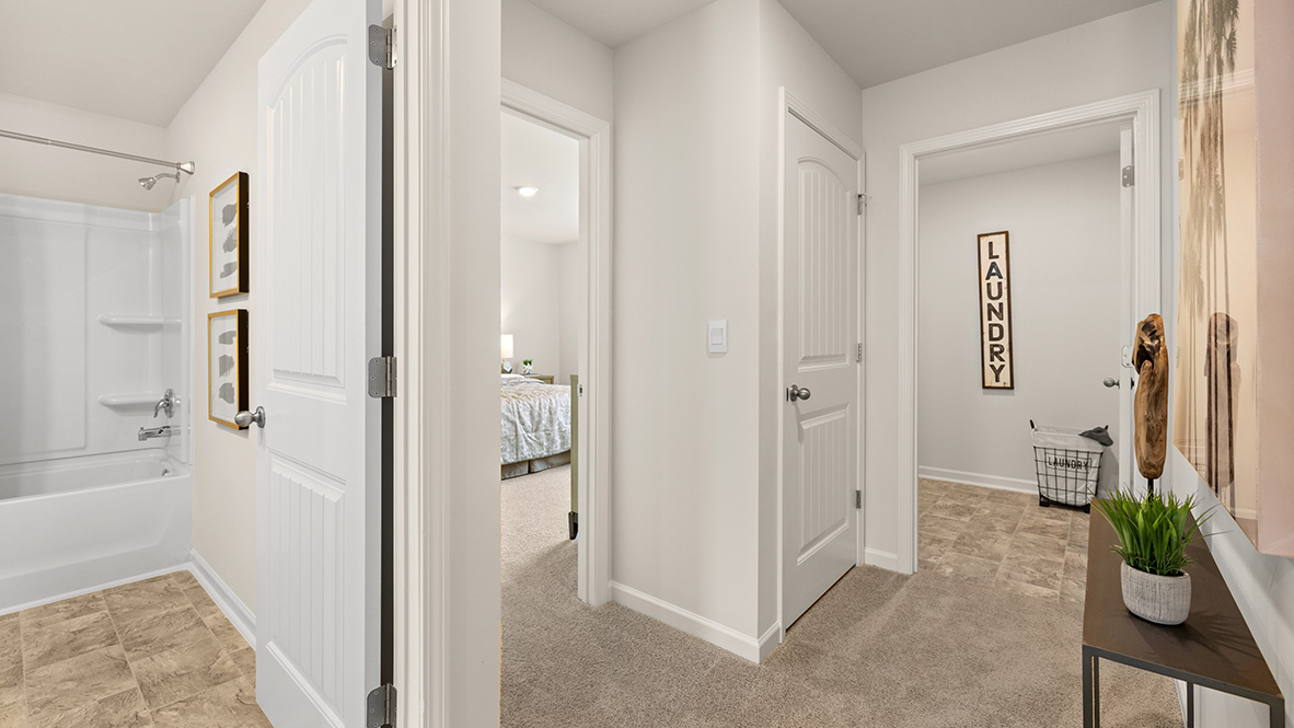 Hallway view of the bathroom, a bedroom, and the laundry room.