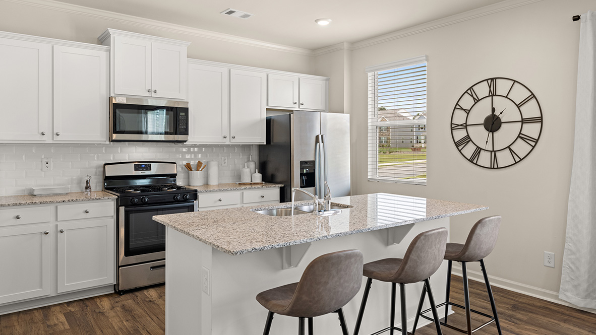 Open-concept kitchen with island sink, white cabinets, stainless steel appliances, and a single kitchen window.