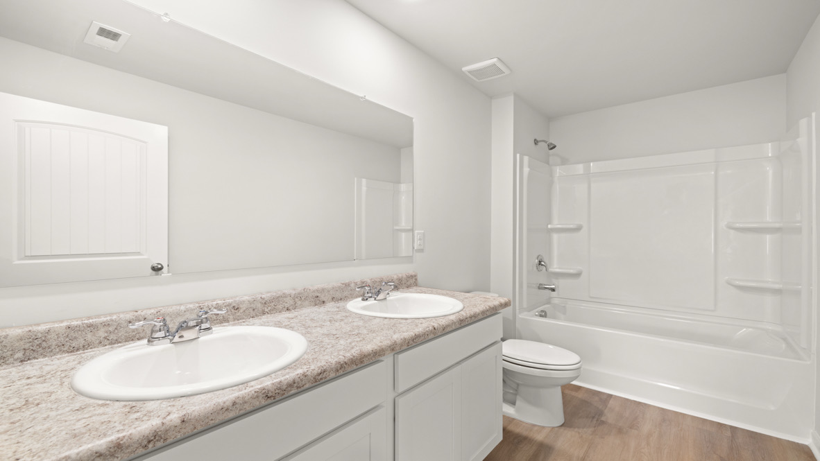 New House secondary bathroom in Oakleigh Glen includes full-length vanity, hard surface countertops, and storage cabinetry crafted by D.R. Horton-Robie Plan