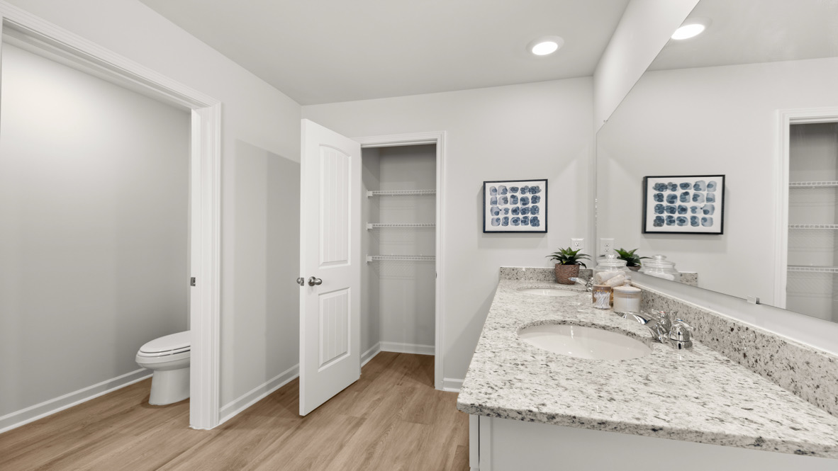 New Construction Home by D.R. Horton includes a private en suite with walk-in shower, hard surface countertops, and ample lighting