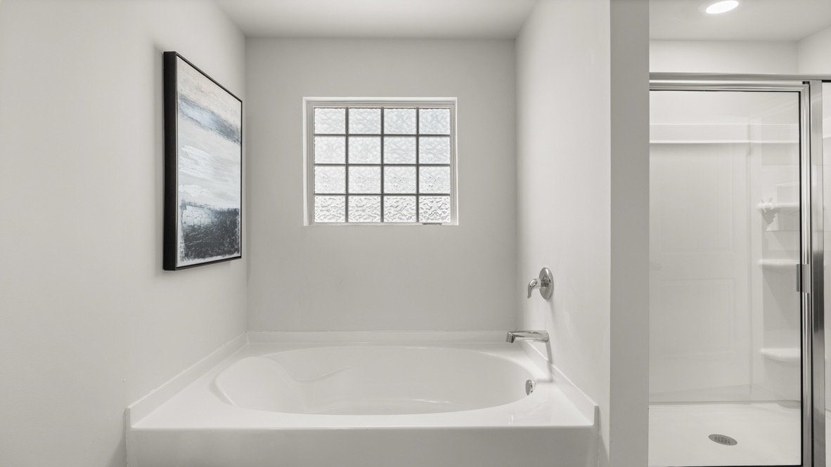 New Construction Home by D.R. Horton includes a private en suite with walk-in shower, hard surface countertops, and ample lighting