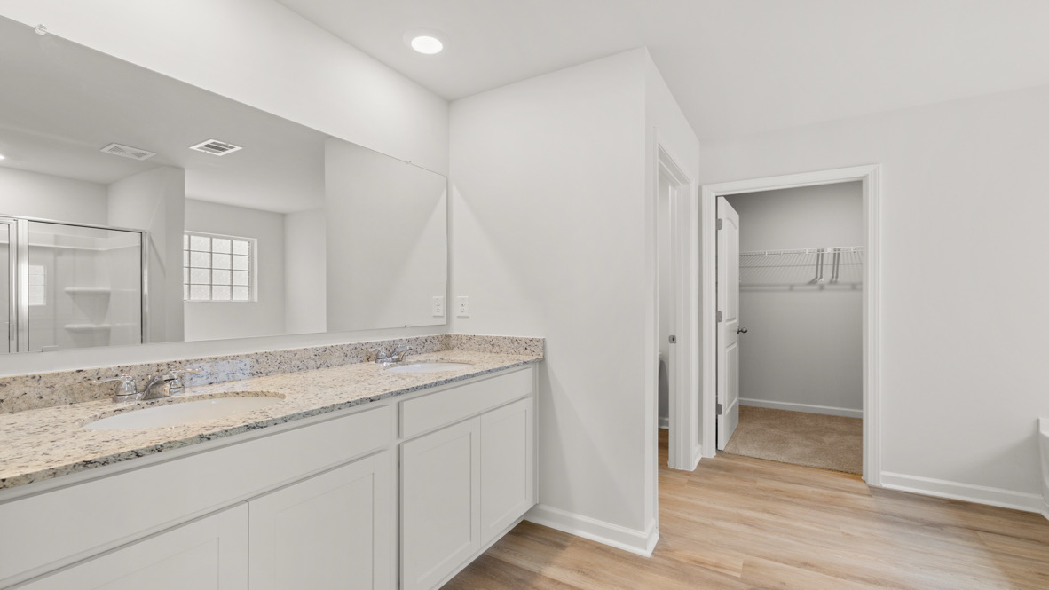 Interior primary bathroom with double sink and walk-in closet