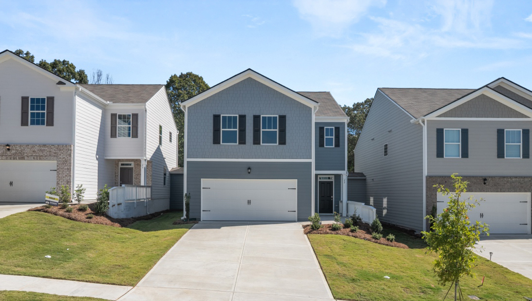 Two-story exterior home with tan and brown bricks, off-white siding, dark gray shutters, a porch, and a two-car garage.