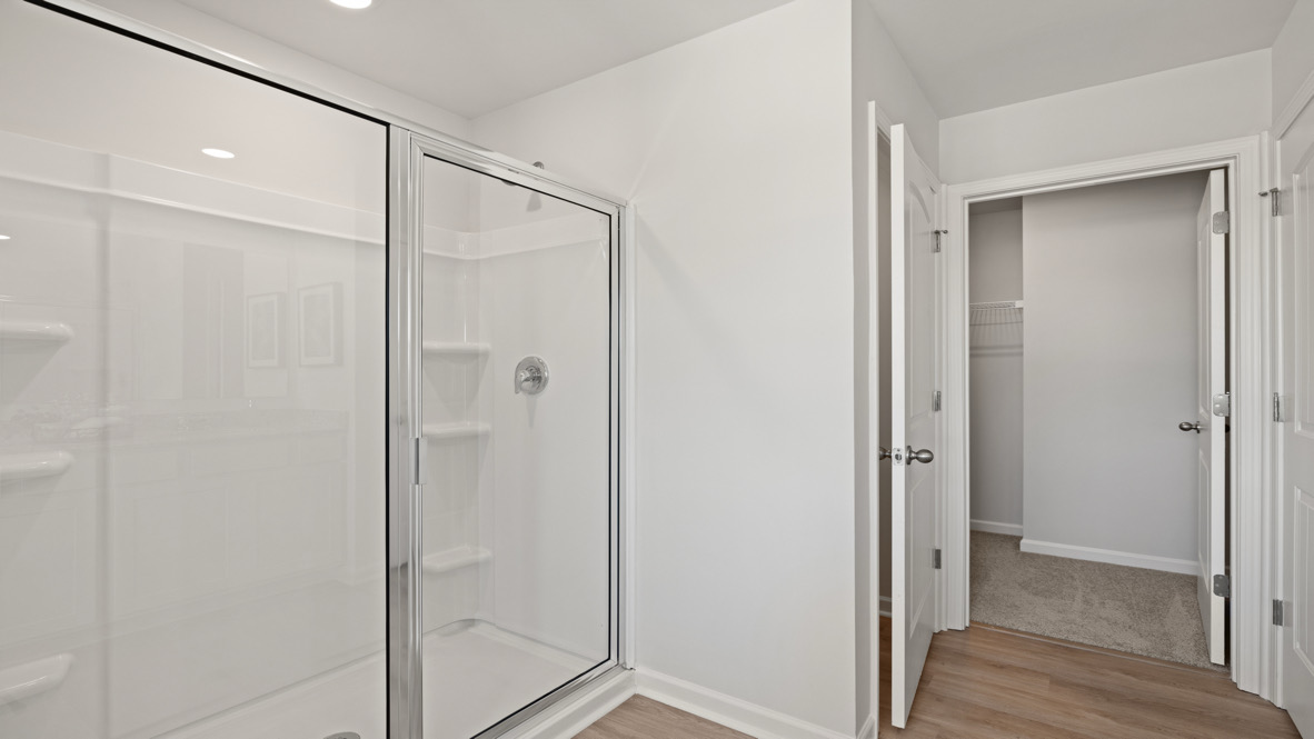 Interior primary bathroom with shower and walk-in closet