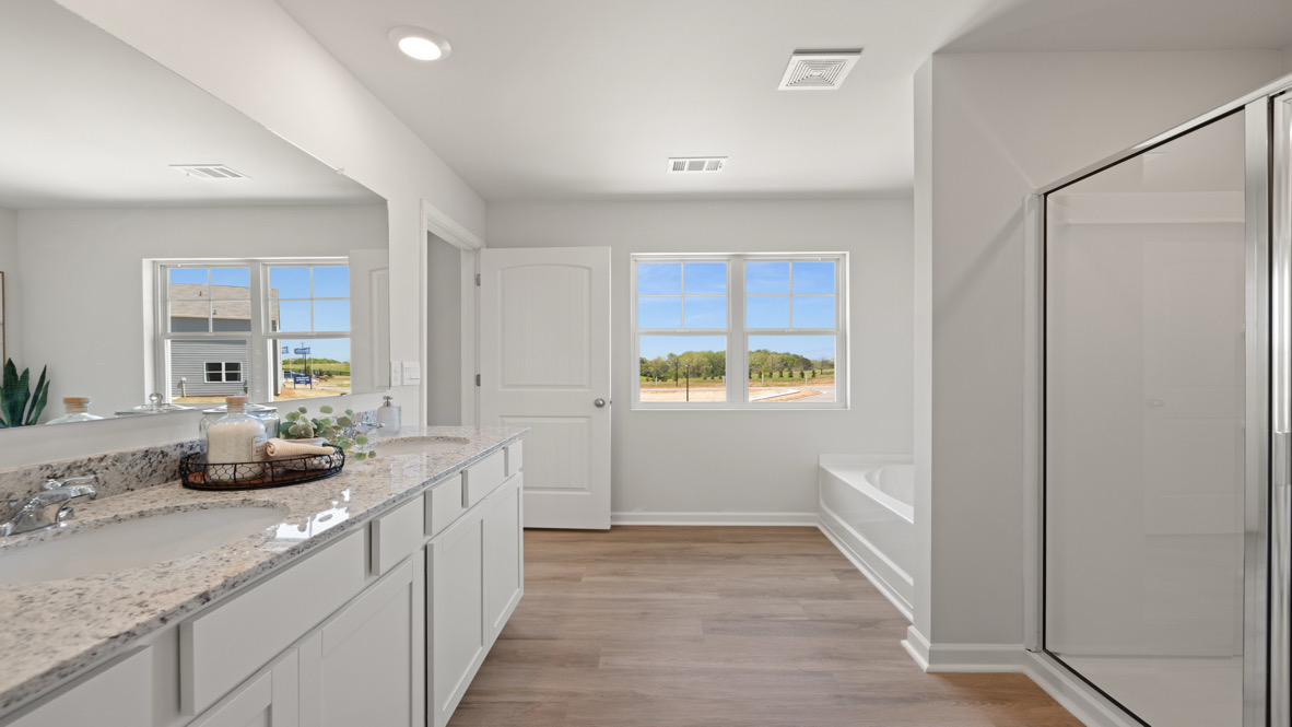 D.R. Horton en suite design with step-in shower, bright overhead lighting, and open access from the primary bedroom