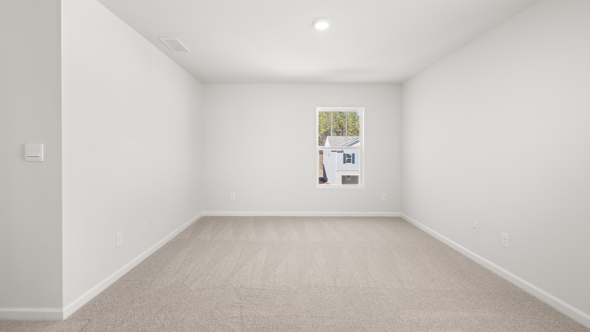 Minimalist empty room with beige carpet and white walls, featuring a single window showing a suburban house and trees outside. Bright and clean atmosphere.
