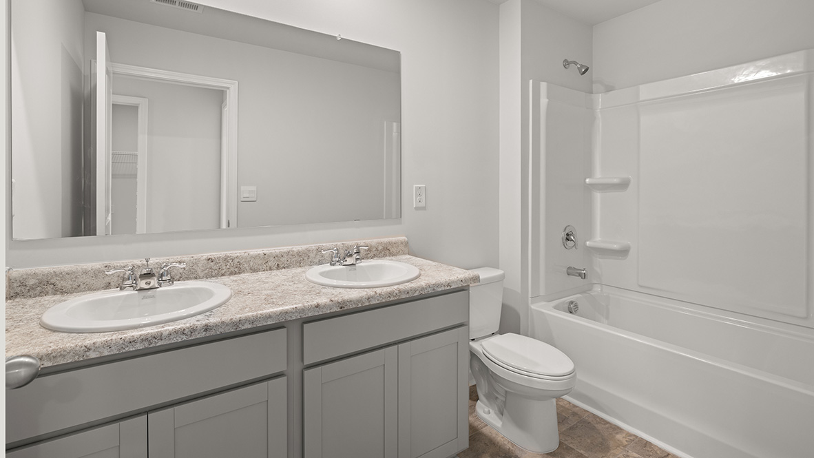 Modern bathroom with dual sinks on a granite countertop, a large mirror, and a white bathtub-shower combo. Clean and minimalistic design.