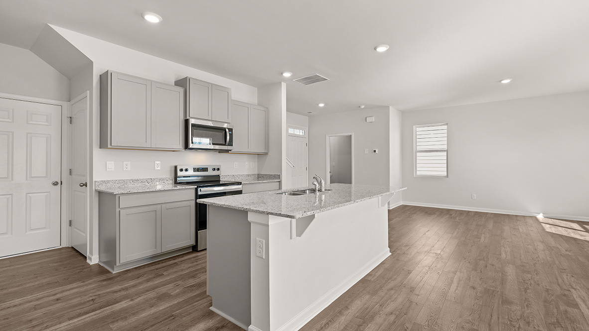 Modern kitchen with gray cabinets, stainless steel appliances, and speckled granite countertops. Bright, open space with wooden floors. Minimalist style.