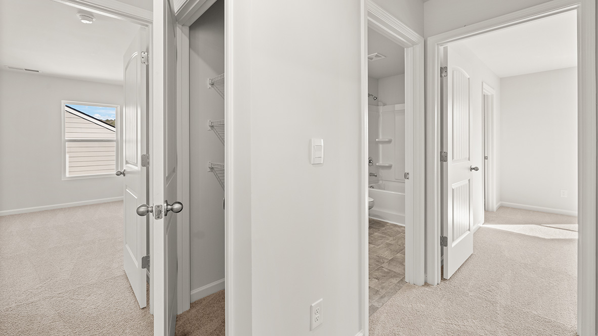 Hallway with three open white doors leading to a bright room with carpet, a closet with shelves, and a bathroom with a bathtub. Minimalist style.