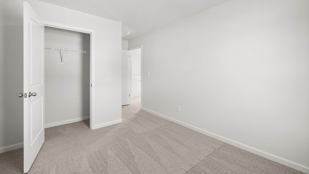 Empty, bright room with light gray walls and carpet. Open closet door reveals white interior. Simple, clean, and minimalist ambiance.