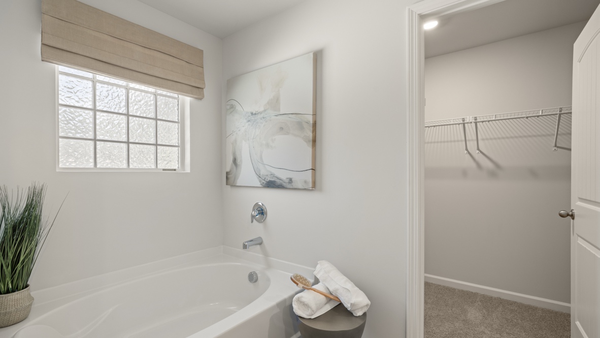 Interior primary bathroom with bath tub and walk-in closet