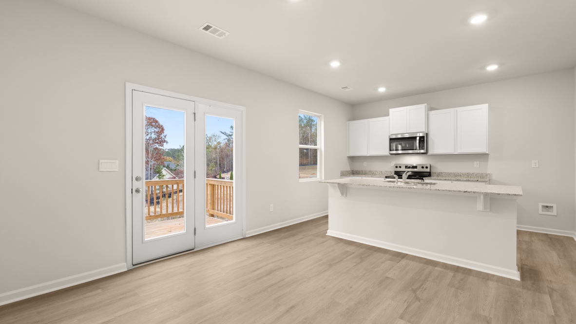 Interior living area open to kitchen with center island and white cabinets