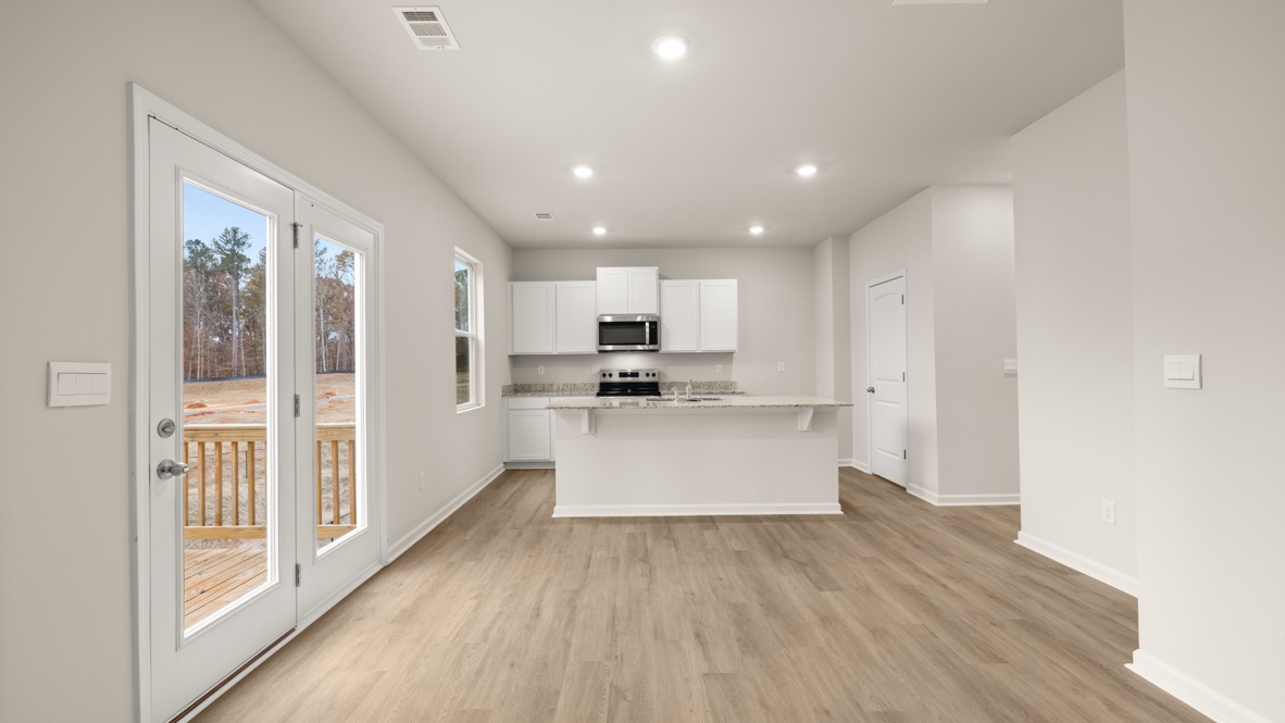 Interior living area open to kitchen with center island and white cabinets