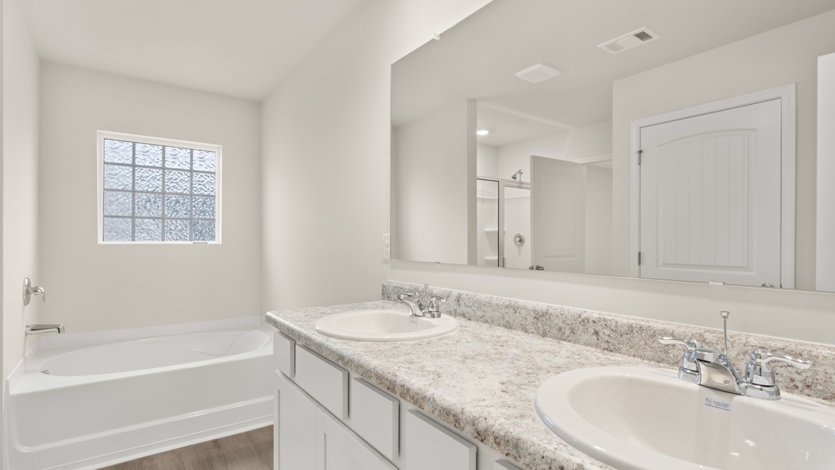Interior primary bathroom with double sink and bath tub