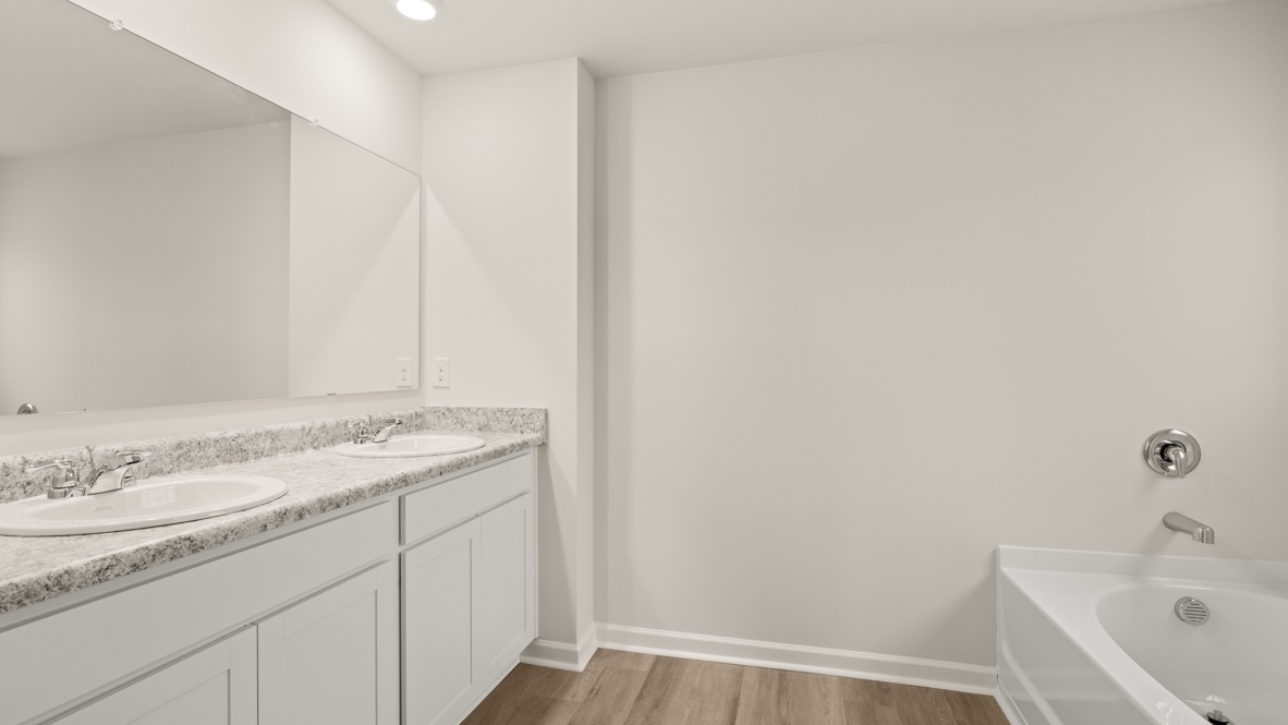 Interior primary bathroom with double sink and bath tub