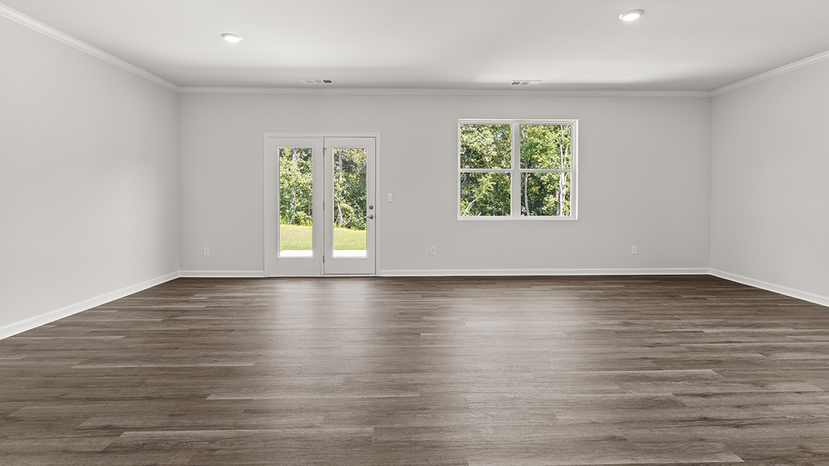 Spacious living room with brown flooring, white walls and windows