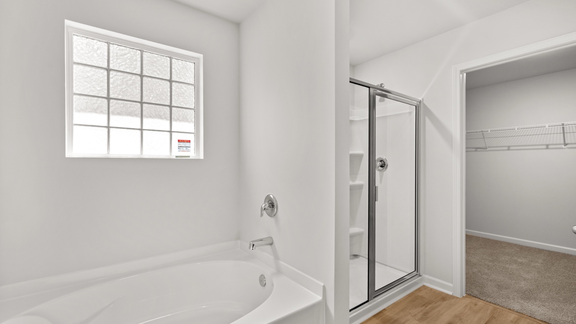 Interior primary bathroom with bath tub and shower and walk-in closet